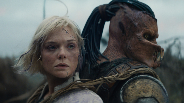 Elle Fanning as Thia carried on the back of Dimitrius Schuster-Koloamatangi as Dek in Predator: Badlands