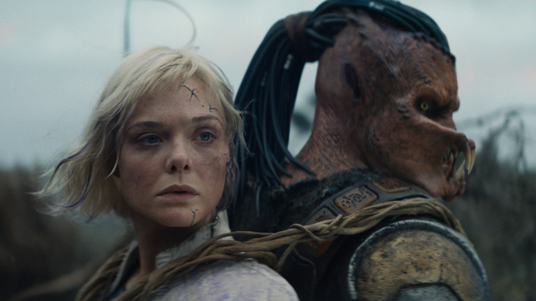 Dimitrius Schuster-Koloamatangi as Dek carrying Elle Fanning as Thia on his back in Predator: Badlands