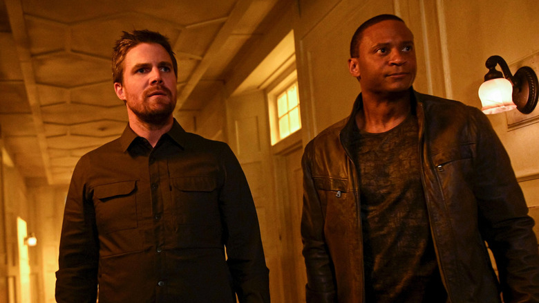 Stephen Amell as Oliver Queen standing by David Ramsey as John Diggle in Arrow Season 8