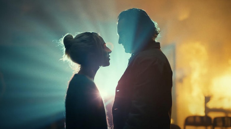 Lady Gaga as Harley Quinn and Joaquin Phoenix as Arthur Fleck looking at one another with a bright light in the background in Joker: Folie a Deux