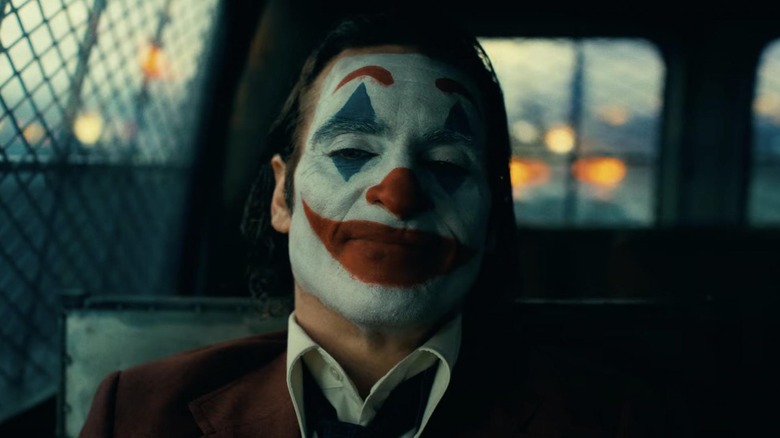 Joaquin Phoenix as Arthur Fleck sitting in the back of a police van in Joker: Folie a Deux