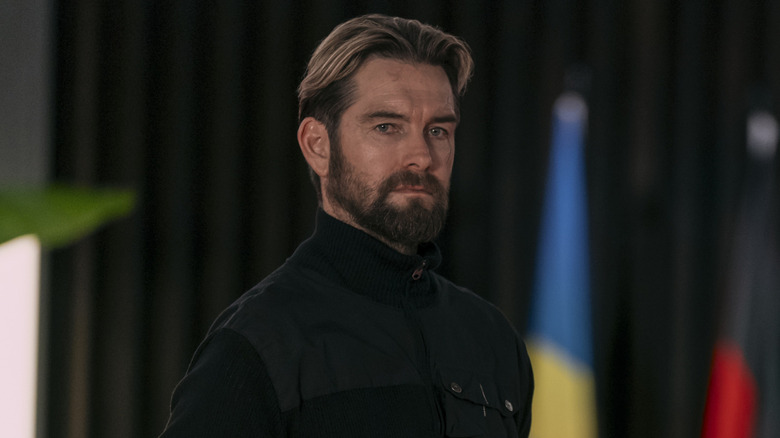 Antony Starr as Rutledge in G20 stood in front of flags