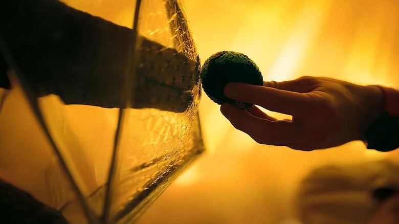 Rocky, through a shield, touching a hacky-sack of Earth in Dr. Grace's hand in Project HAil Mary