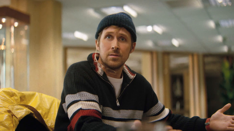 ப்ராஜெக்ட் ஹெயில் மேரியில் டேபிளில் அமர்ந்திருக்கும் ஆச்சரியத்துடன் பீனி அணிந்த ரைலாண்டாக ரியான் கோஸ்லிங்