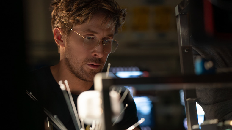 Ryan Gosling as astronaut Ryland Grace sitting at a desk and wearing glasses in Project Hail Mary