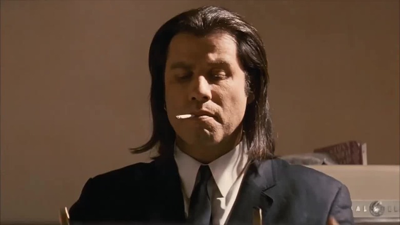 John Travolta como Vincent Vega segurando a maleta em Pulp Fiction