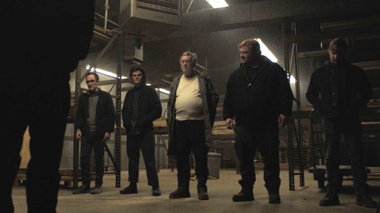 A group of men standing in a warehouse in "The Standoff at Sparrow Creek"