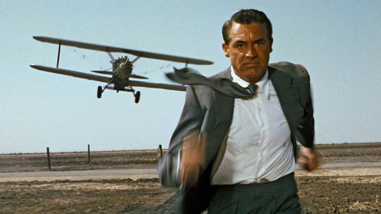 Cary Grant as Thornhill in grey suit running with airplane flying behind him in North By Northwest