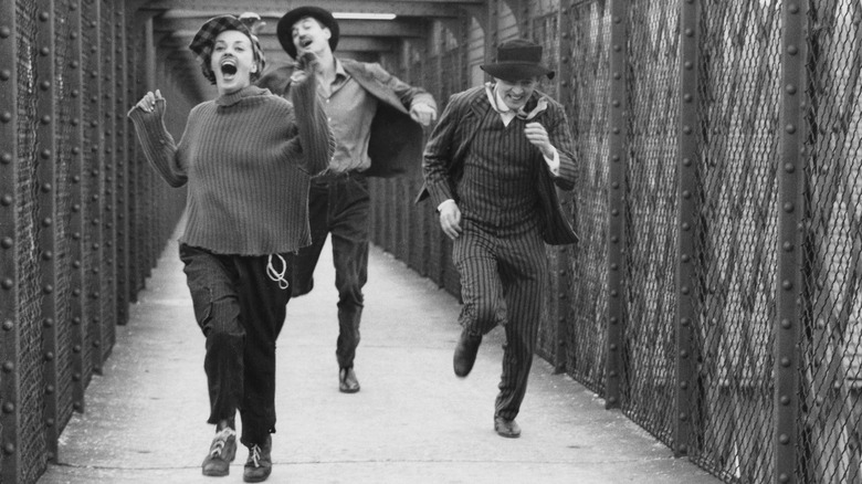 Jeanne Moreau as Catherine running across bridge with Henri Serre as Jim and Oskar Werner as Jules in Jules and Jim