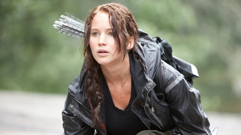 Jennifer Lawrence as Katniss crouching with bows on her back in The Hunger Games