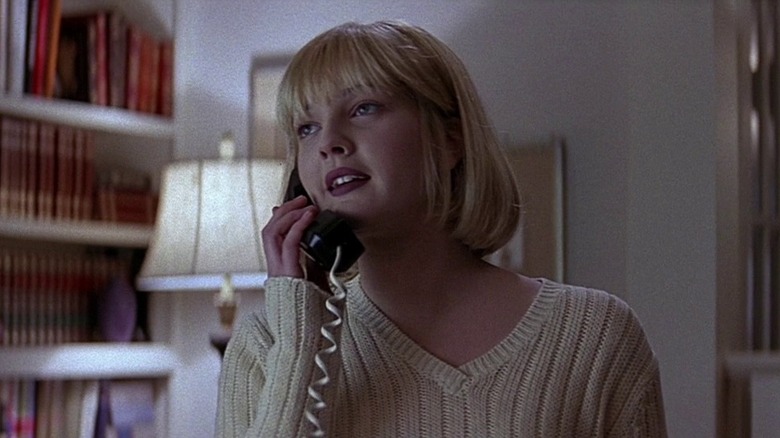 Drew Barrymore with blonde hair and bangs as Casey talking on a chorded telephone in Scream