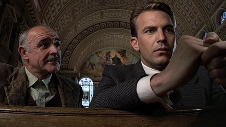 Kevin Costner as Eliot Ness sits in a pew next to Sean Connery's Jim Malone in The Untouchables