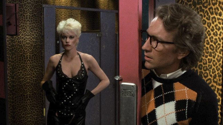 Melanie Griffith wears a black dress as Holly Body while Craig Wasson's Jake pokes his head in her dressing room to look at her in Body Double