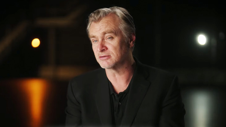 Christopher Nolan sits in a dark room during an interview behind the scenes of The Odyssey