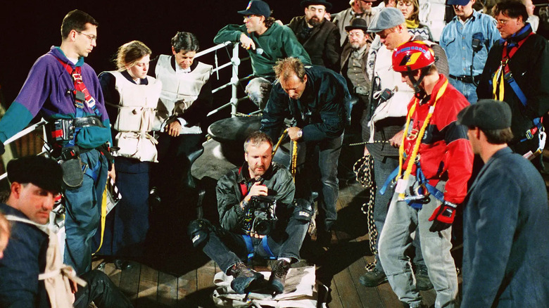 Director James Cameron surrounded by cast and crew members on the set of Titanic