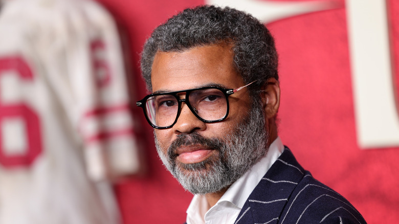 Jordan Peele with a beard wearing glasses