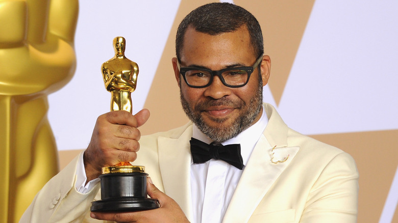 Jordan Peele holding his Academy Award