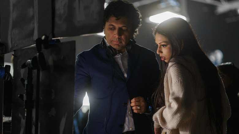 Director M. Night Shyamalan standing by a monitor with his daughter Saleka Night Shyamalan as Lady Raven on the set of Trap
