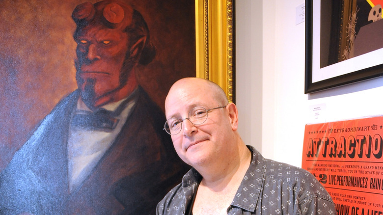 Mike Mignola standing next to portrait of Hellboy in suit