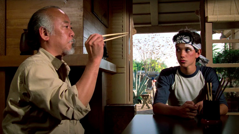 Ralph Macchio watches Pat Morita attempt to catch a fly with chopsticks in The Karate Kid