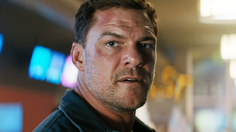 Alan Ritchson's Jack Reacher is seen in closeup as he stands in a bowling alley in Reacher