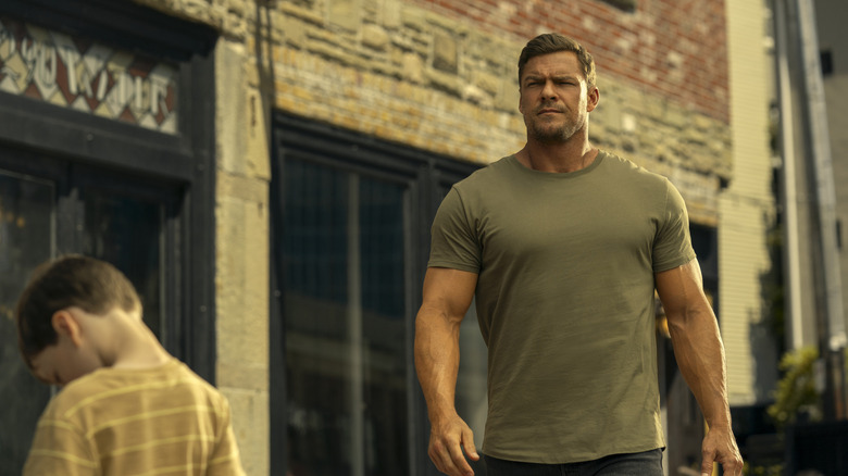 Big guy Reacher strutting down the street with his huge arms in Reacher season 3