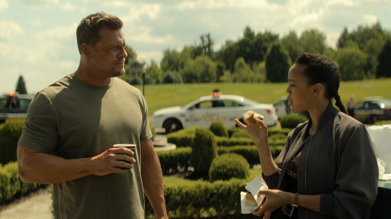 Alan Ritchson as Jack Reacher stands outside opposite Maria Sten as Frances Neagely in Reacher