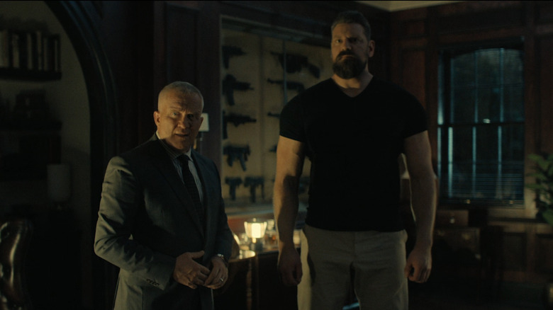 Anthony Michael Hall as Zachary Beck and Olivier Richters as Paulie stand side by side in Beck's mansion in Reacher