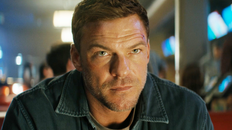 Alan Ritchson's Jack Reacher is seen in closeup as he sits in a bowling alley in Reacher