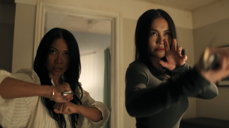 Agnez Mo's Lila Hoth and Anggun's Amisha Hoth stand side by side in a hotel room holding karambits in Reacher