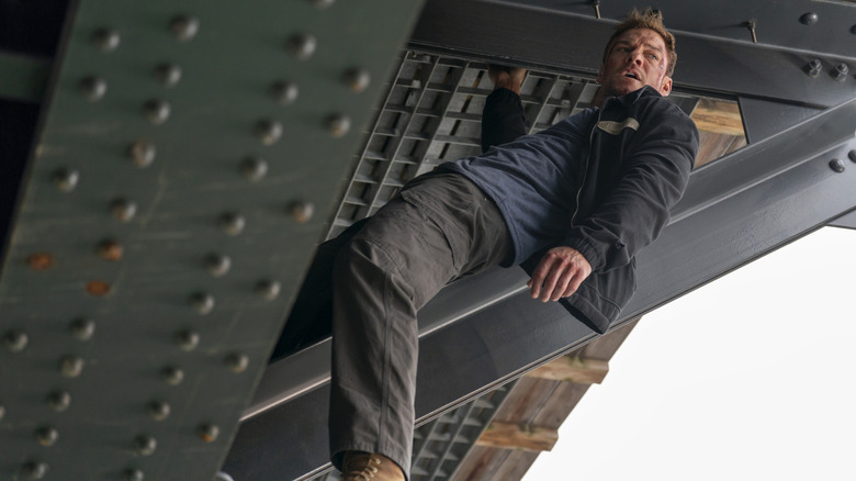 Jack Reacher hanging from a bridge with only one supermarker-chicken-sized hand in Reacher