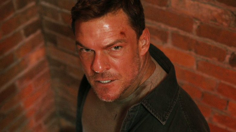 Alan Ritchson's Jack Reacher is seen looking angry in closeup from a high angle in Reacher