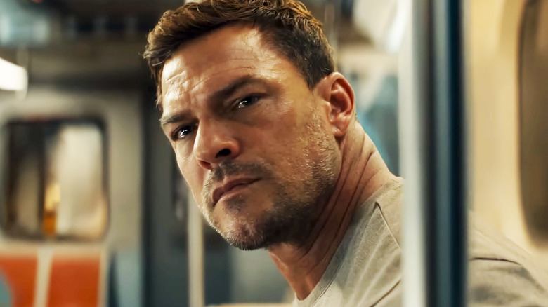 Alan Ritchson's Jack Reacher leans forward on a subway car in Reacher