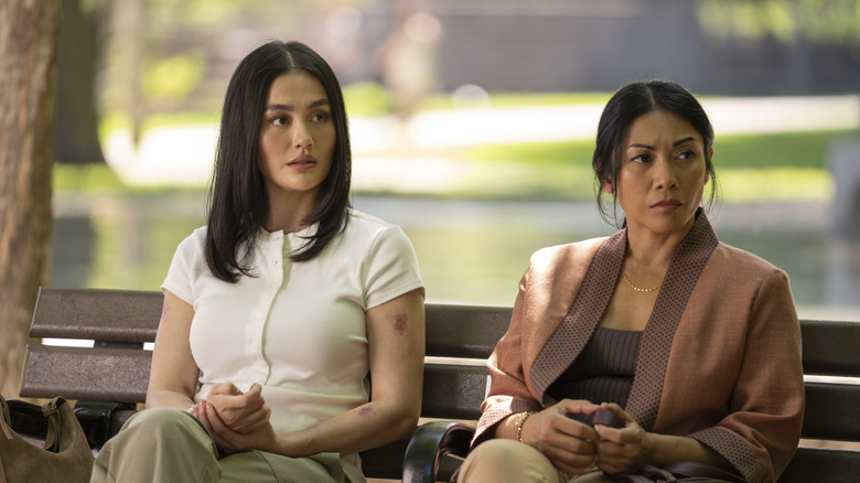 Agnez Mo as Lila Hoth sitting on a park bench next to Anggun as Amisha in Reacher