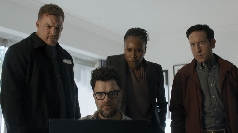 Alan Ritchson as Jack Reacher standing by a computer next to Sydelle Noel as Tamara Green, Chris Marquette as Jacob Merrick, and Kevin Weisman as Russell Plum in Reacher