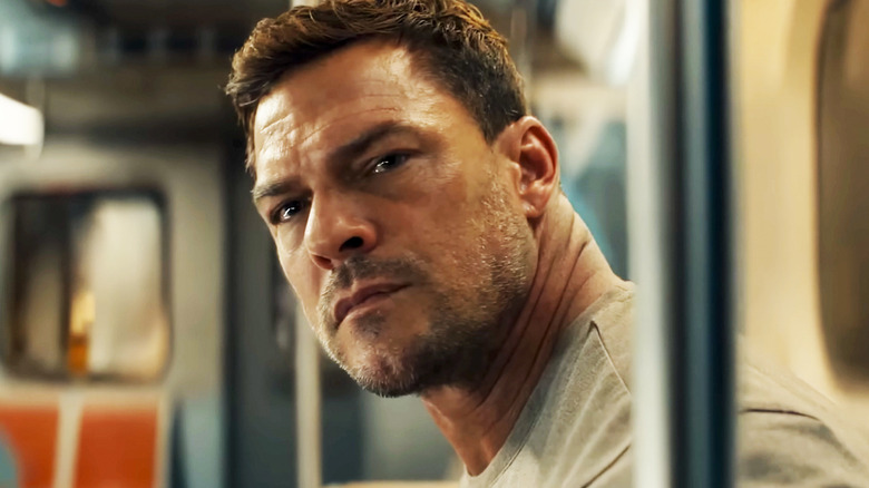 Alan Ritchson's Jack Reacher leans forward on a subway car in Reacher