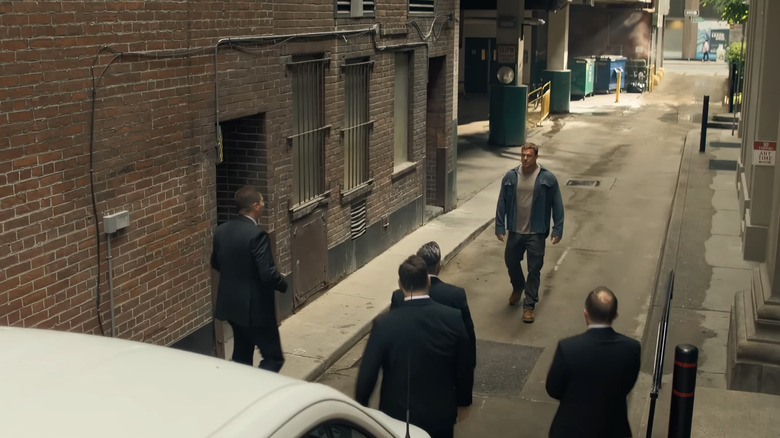 Alan Ritchson's Jack Reacher is approached by a gang of men in an alley in Reacher