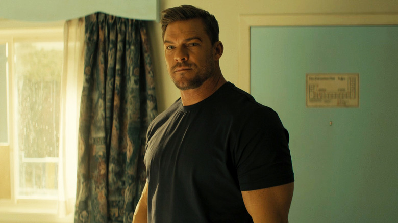 Alan Ritchson's Jack Reacher stands in a motel room in Reacher