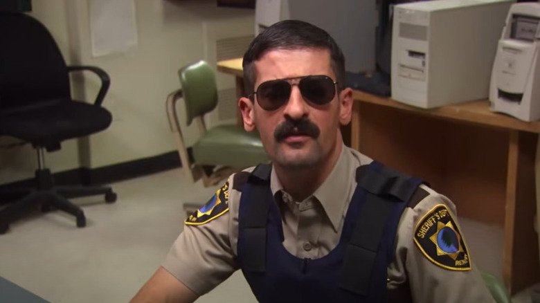 Robert Ben Garant as Dep. Travis Junior sits at his desk in Reno 911.