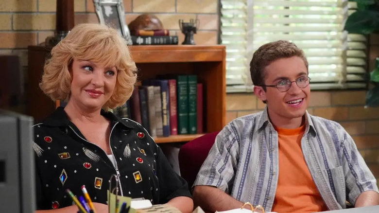 Wendi McLendon-Covey sits in the principal's office in The Goldbergs.