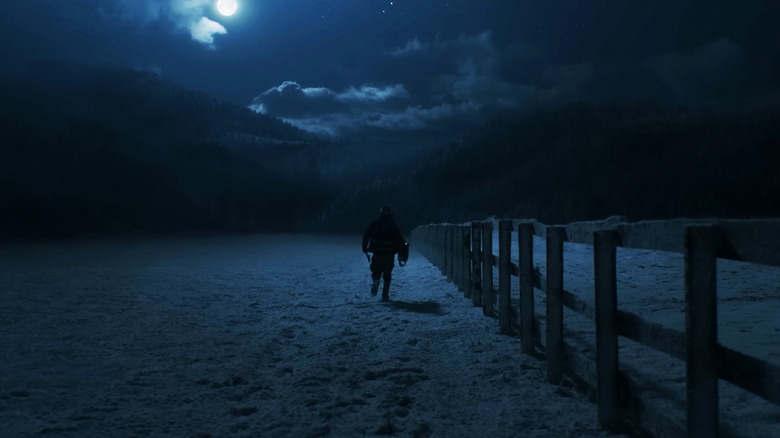 Austin Abrams' Bryan runs next to a fence in a snow covered field in Resident Evil