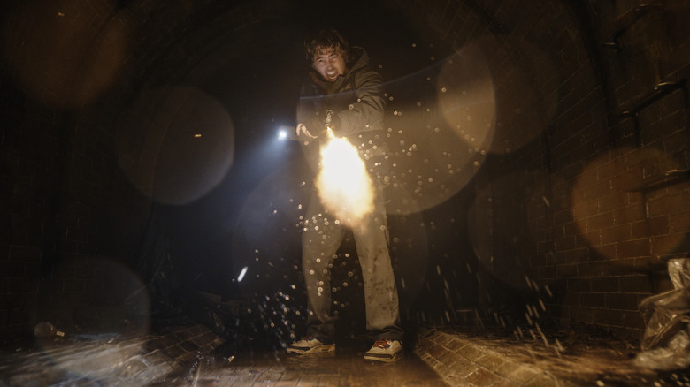 Bryan firing a gun at an unseen object in a sewer in Resident Evil (2026)