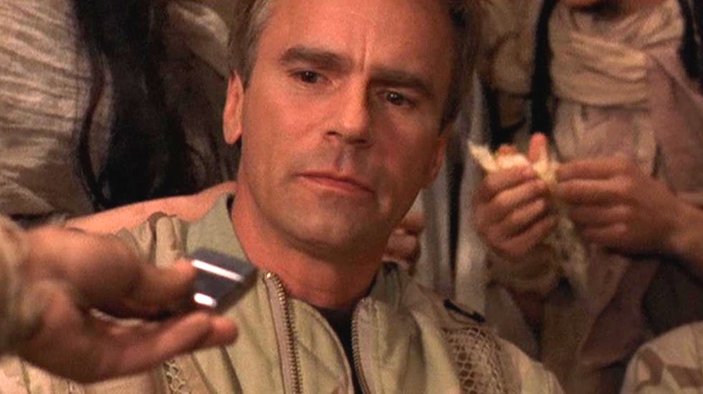 Richard Dean Anderson as Jack O'Neill being handed a lighter in Stargate SG-1 Season 1