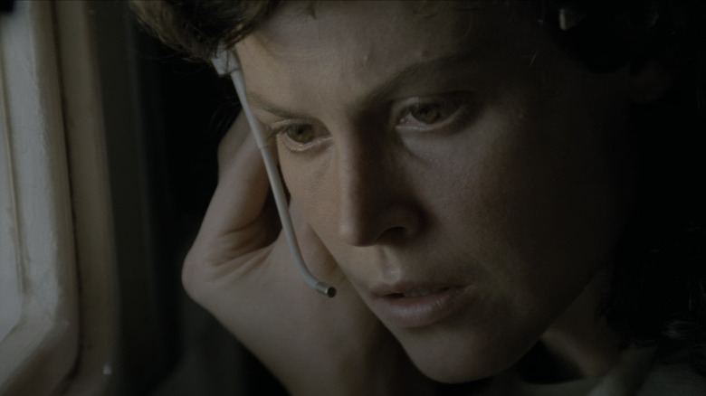 Ellen Ripley listens intently to a communication on her earpiece in Alien