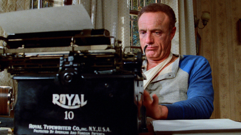 James Caan as Paul Sheldon typing on a typewriter in Misery