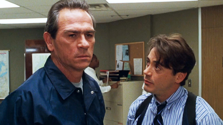 Robert Downey Jr. as AGENT John ROYCE considers Tommy Lee Jones as head of American marshal Samuel Gerard as they stand in an office in the American marshals
