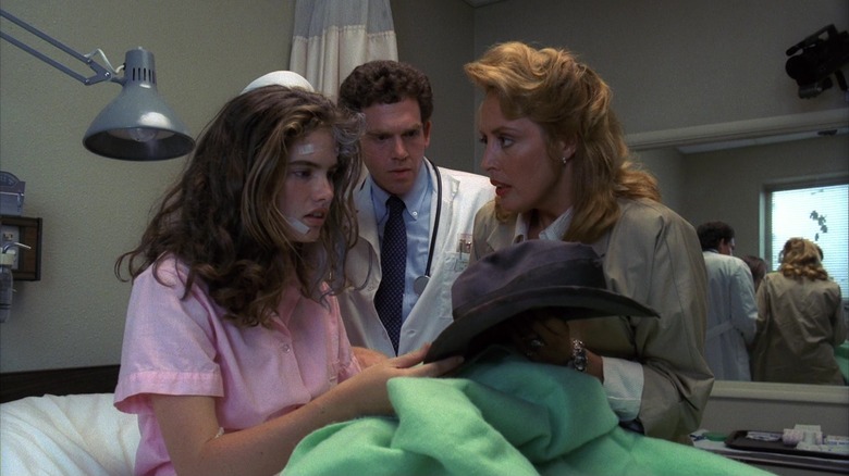 Nancy holding Freddy's hat in bed while a dream technician and her mom look on in A Nightmare on Elm Street