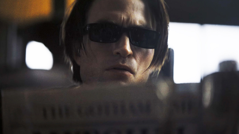 Robert Pattinon's Bruce Wayne wears shades as he reads a newspaper in The Batman