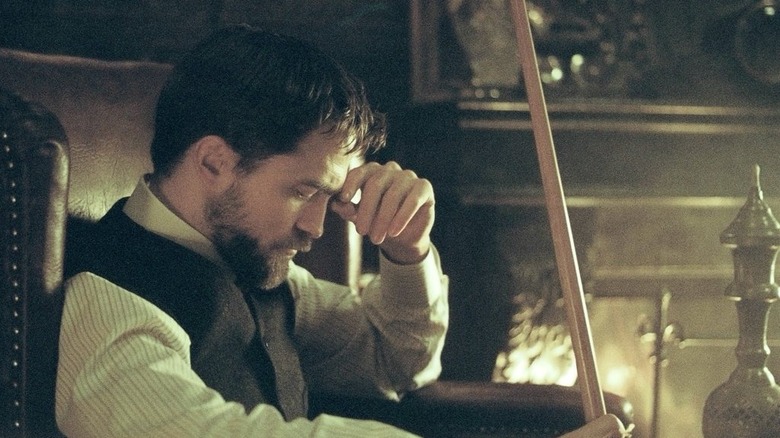 Marker reading in front of a fire in The Childhood of a Leader
