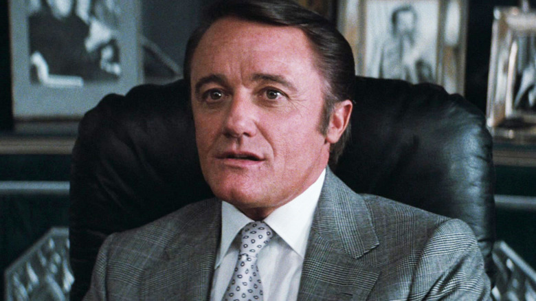 Robert Vaughn's Ross Webster sits at his desk in Superman III